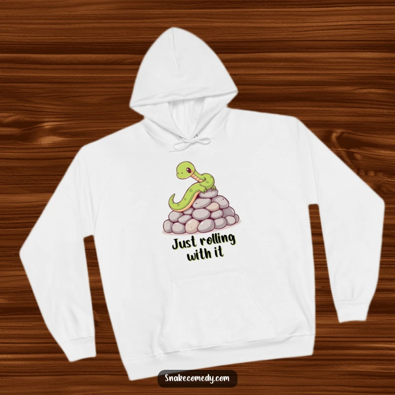 Funny hoodie depicting a cartoon snake comically losing its footing and slipping on a collection of smooth, round stones, looking surprised.